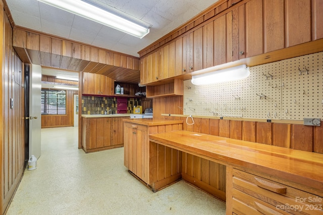 kitchen with butcher block countertops, sink, and wooden walls