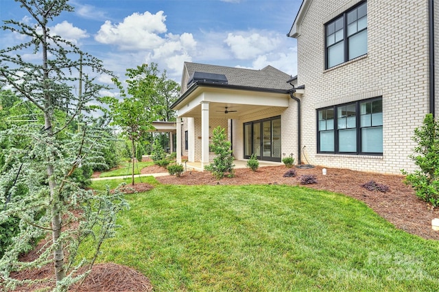 rear view of property featuring ceiling fan and a lawn