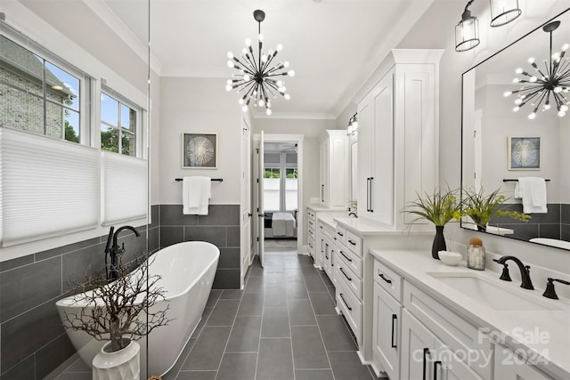 bathroom featuring tile walls, an inviting chandelier, a tub to relax in, and plenty of natural light