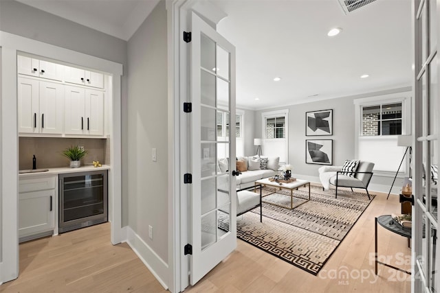 interior space featuring french doors, beverage cooler, light hardwood / wood-style floors, and white cabinetry