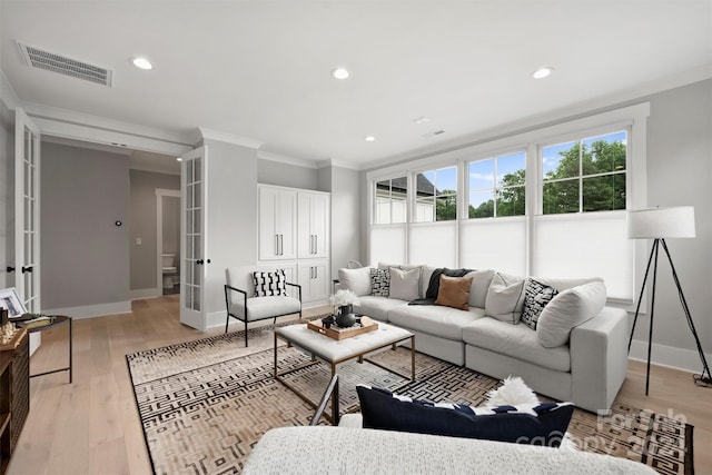 living room with ornamental molding, french doors, and light hardwood / wood-style flooring