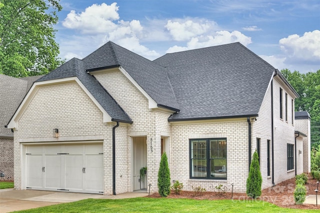 french provincial home with a garage, brick siding, a shingled roof, and concrete driveway