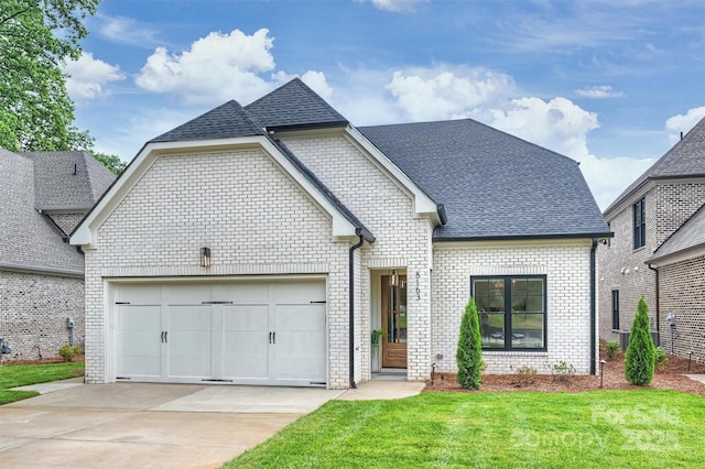 french country style house with concrete driveway, a garage, a shingled roof, and brick siding