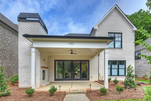 view of exterior entry featuring brick siding, french doors, and a ceiling fan