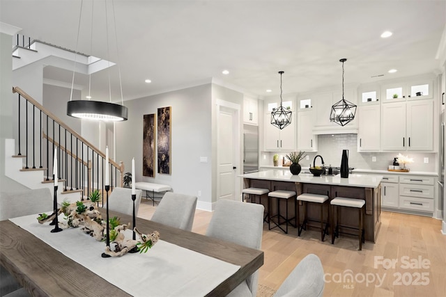 dining room with light wood-type flooring, recessed lighting, and stairs