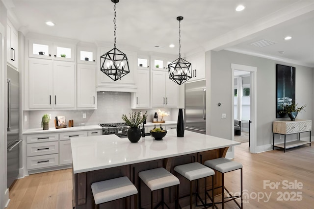 kitchen with built in refrigerator, recessed lighting, decorative backsplash, a kitchen bar, and a notable chandelier
