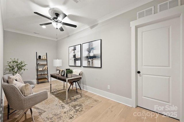 home office with a ceiling fan, visible vents, light wood-style flooring, baseboards, and ornamental molding