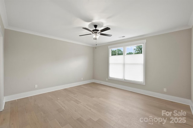 empty room with baseboards, ceiling fan, light wood finished floors, and crown molding