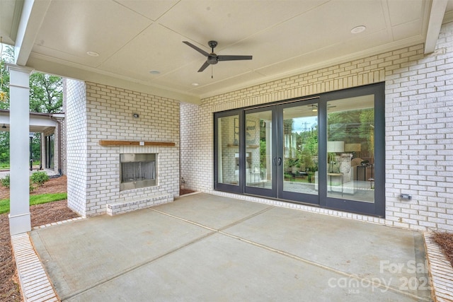 view of patio with an outdoor brick fireplace, a ceiling fan, and french doors