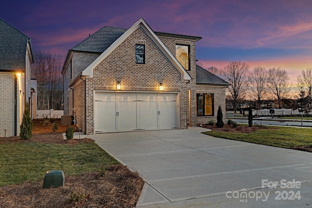 front facade featuring a lawn, central air condition unit, and a garage