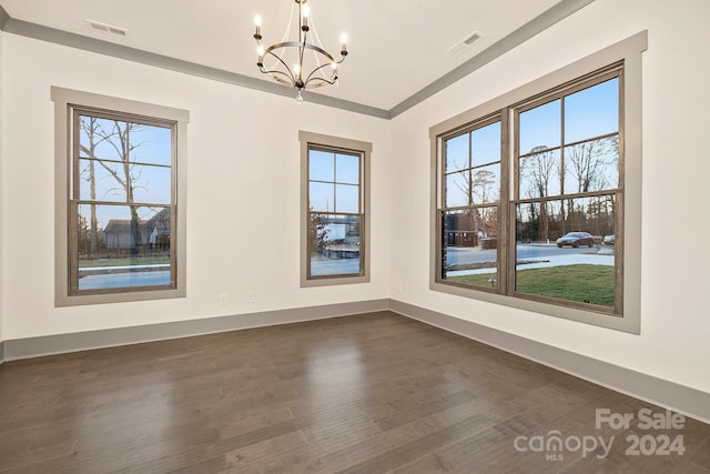 spare room with dark hardwood / wood-style flooring and a chandelier