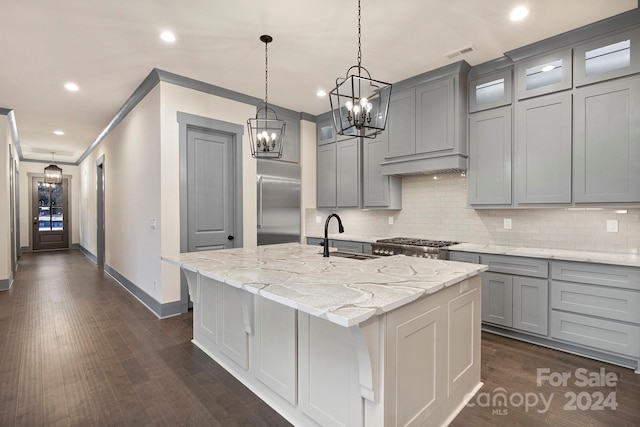 kitchen featuring an island with sink, crown molding, dark hardwood / wood-style flooring, light stone countertops, and stainless steel built in fridge