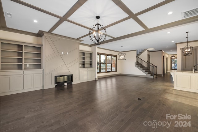 unfurnished living room featuring a notable chandelier, coffered ceiling, dark hardwood / wood-style flooring, built in shelves, and ornamental molding