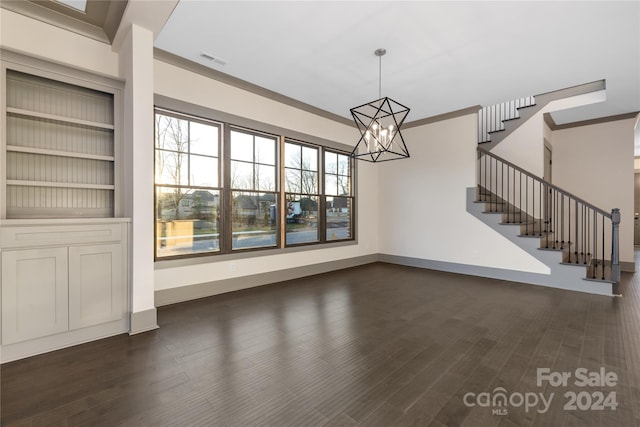 unfurnished living room featuring built in shelves, crown molding, a notable chandelier, and dark wood-type flooring