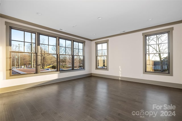 unfurnished room featuring crown molding, dark wood-type flooring, and a healthy amount of sunlight