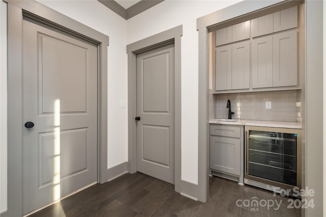 bar featuring wine cooler, gray cabinets, tasteful backsplash, dark hardwood / wood-style flooring, and sink