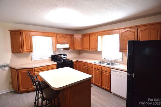 kitchen featuring sink, light hardwood / wood-style floors, a wealth of natural light, and black appliances