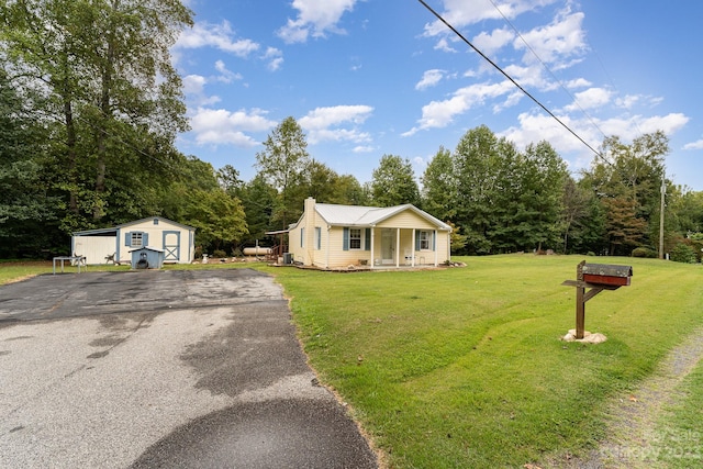 view of front facade featuring a front lawn, a storage shed, and covered porch