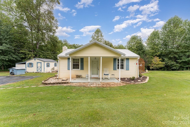 view of front of home featuring a patio, a front lawn, and a shed