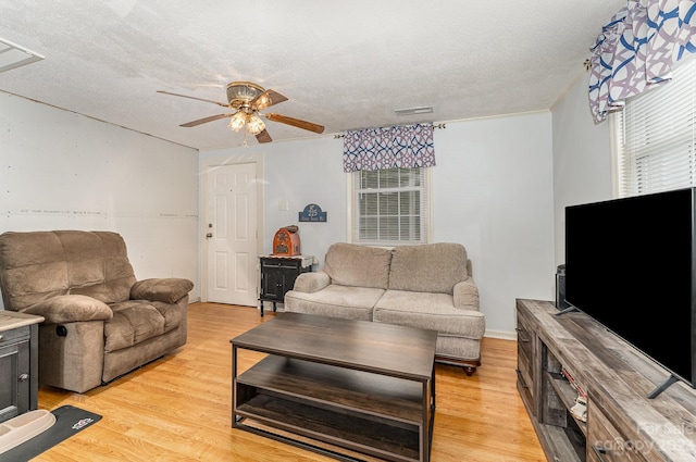 living room featuring a textured ceiling, ceiling fan, and light wood-type flooring