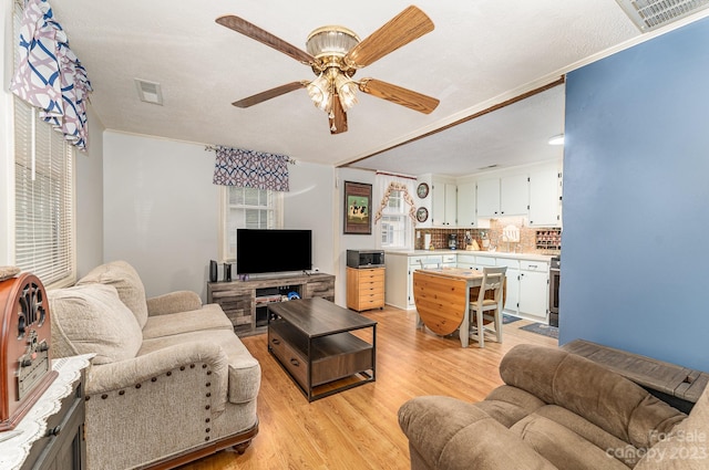 living room with light hardwood / wood-style floors, ceiling fan, a textured ceiling, and crown molding