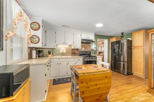 kitchen with white cabinetry, appliances with stainless steel finishes, tasteful backsplash, and light hardwood / wood-style floors