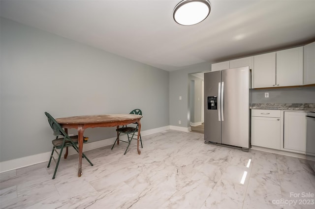 kitchen with stainless steel appliances, stone countertops, white cabinets, and light tile floors