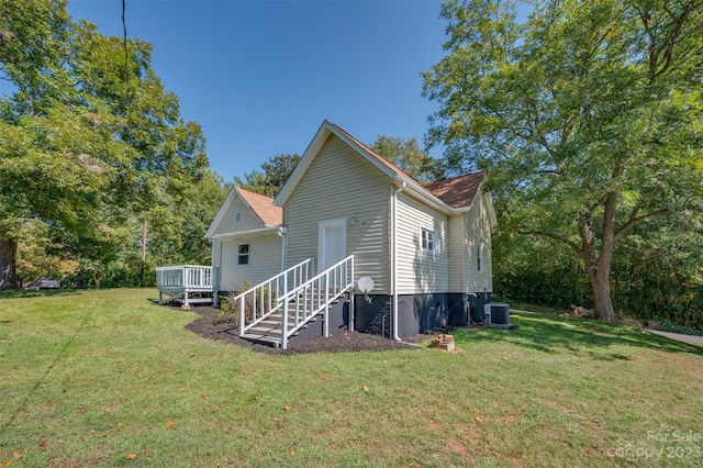 rear view of property with central AC, a deck, and a yard