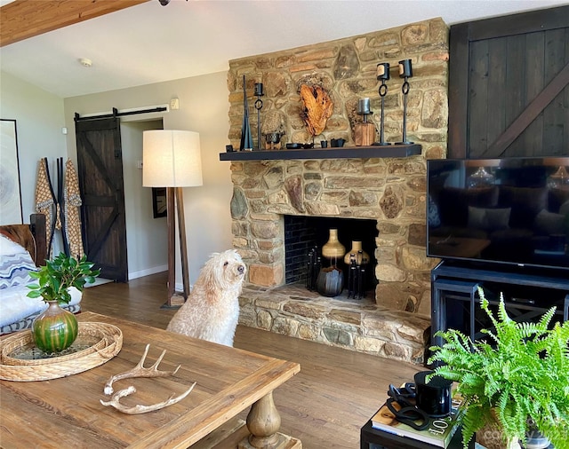 living room featuring dark hardwood / wood-style flooring, a stone fireplace, and a barn door