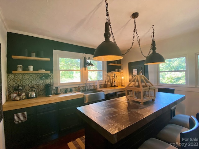 kitchen featuring backsplash, plenty of natural light, pendant lighting, and sink