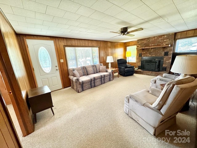 carpeted living room featuring ceiling fan and wood walls