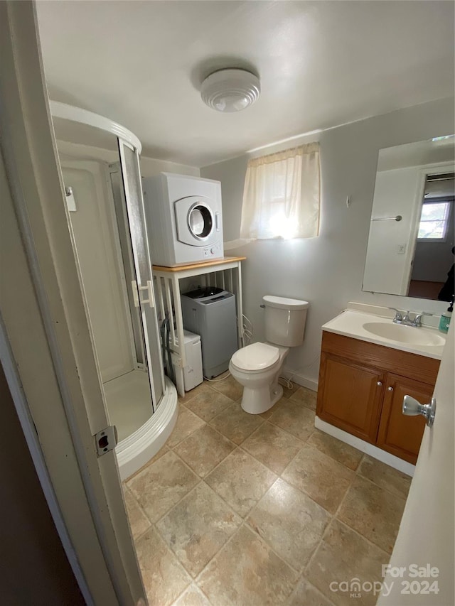 bathroom featuring washer / clothes dryer, vanity, toilet, and a shower with door