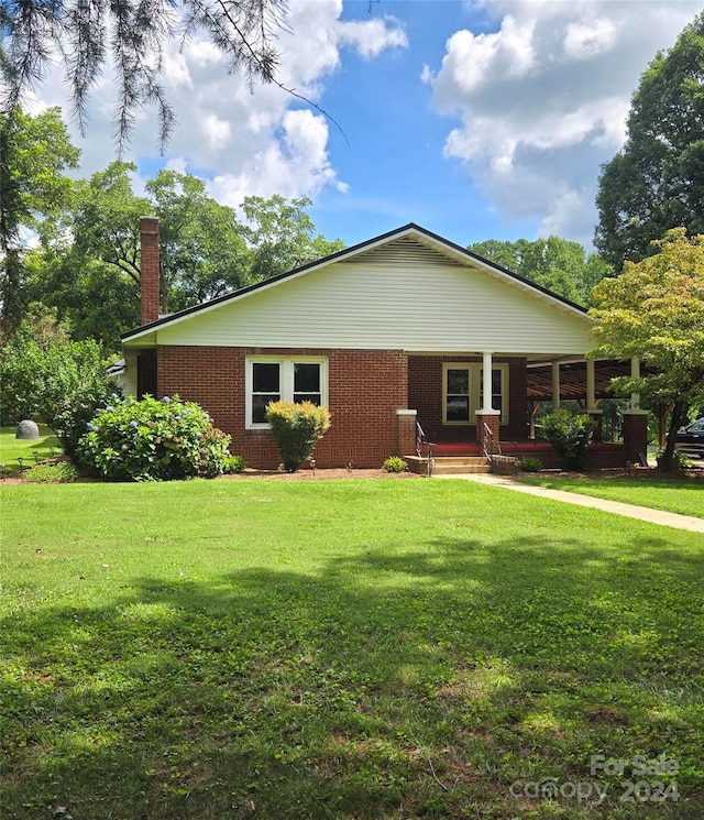 ranch-style home featuring covered porch and a front yard