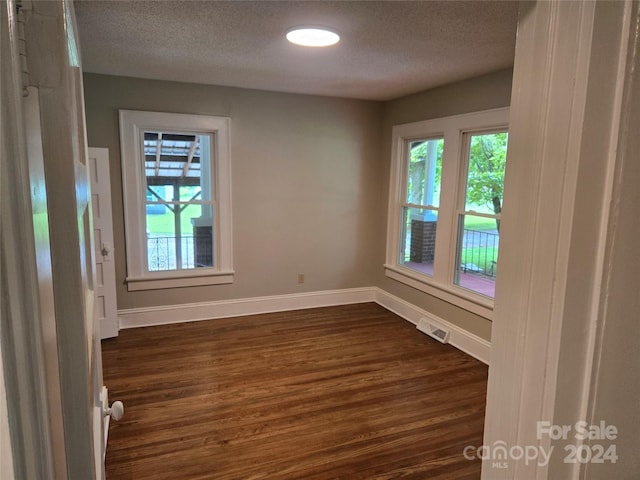 empty room with dark wood-type flooring and a textured ceiling