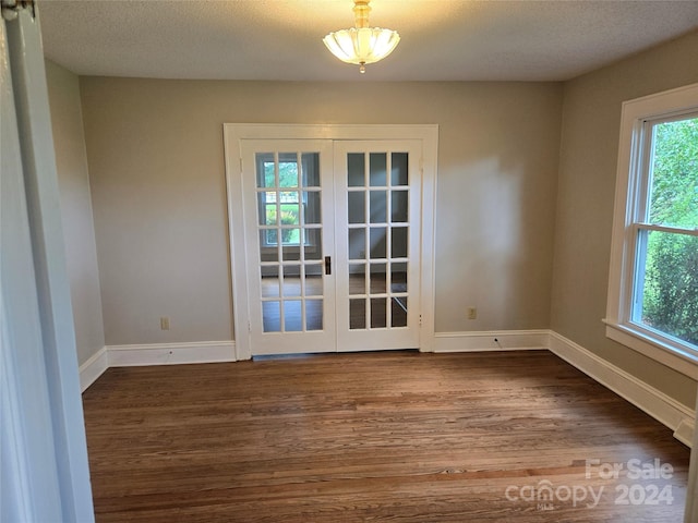 interior space with plenty of natural light, hardwood / wood-style floors, a textured ceiling, and french doors