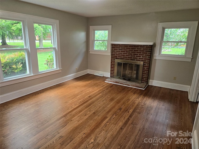 unfurnished living room with a brick fireplace and dark hardwood / wood-style floors