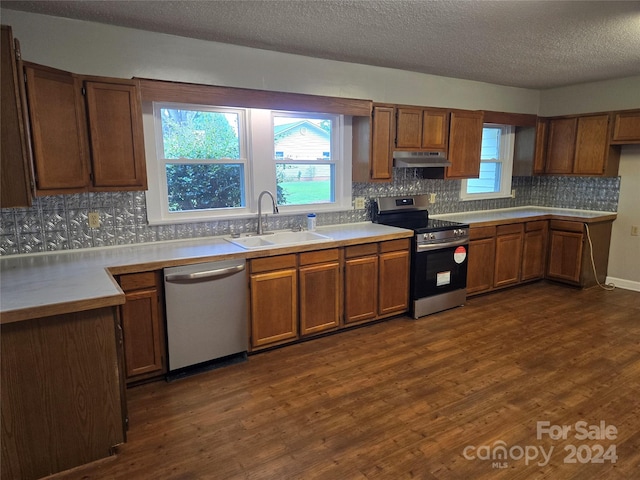 kitchen with a textured ceiling, stainless steel appliances, a healthy amount of sunlight, sink, and dark hardwood / wood-style floors