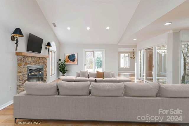 living room featuring lofted ceiling, a fireplace, and light wood-type flooring