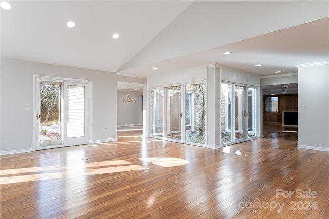 unfurnished living room with high vaulted ceiling, hardwood / wood-style flooring, and an inviting chandelier