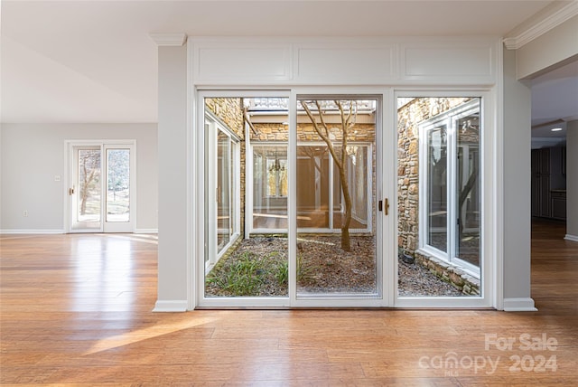 doorway to outside with ornamental molding and hardwood / wood-style floors