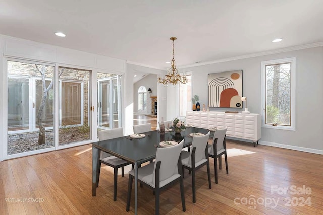 dining area featuring light hardwood / wood-style floors, crown molding, and an inviting chandelier