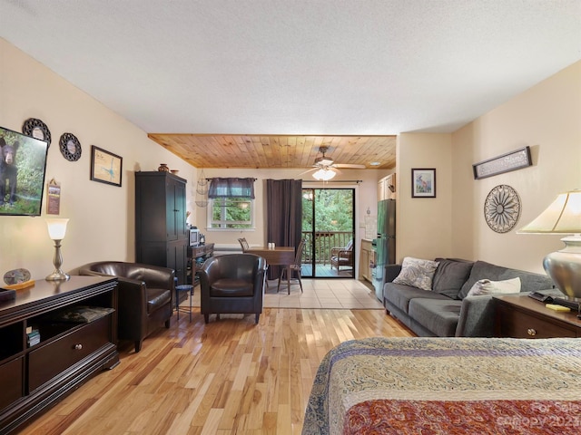 living room with ceiling fan, a textured ceiling, light wood-type flooring, and wooden ceiling