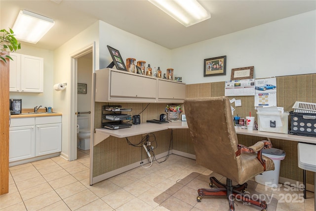 office space with built in desk, light tile patterned floors, and a sink