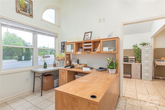office space with a high ceiling, baseboards, and light tile patterned floors