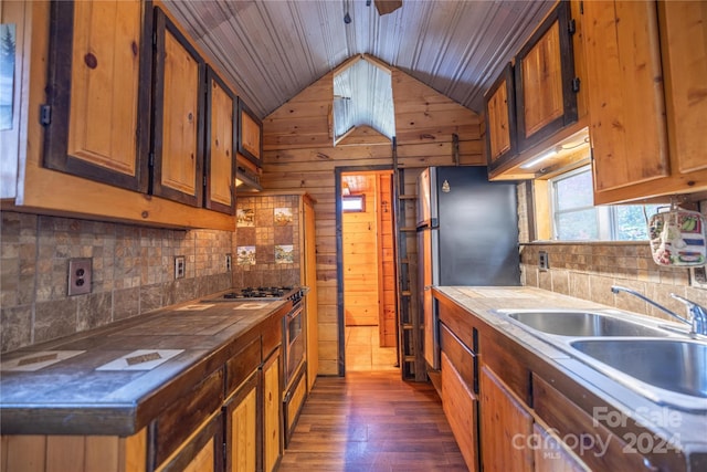 kitchen featuring lofted ceiling, dark wood-type flooring, wooden ceiling, sink, and wooden walls