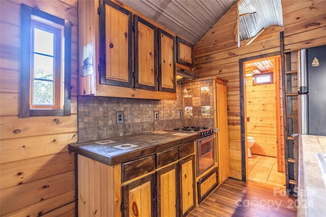 kitchen with tasteful backsplash, wooden walls, wood-type flooring, wooden ceiling, and lofted ceiling