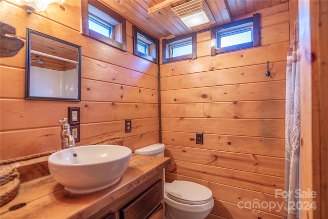 bathroom with wooden walls, wood ceiling, and a wealth of natural light