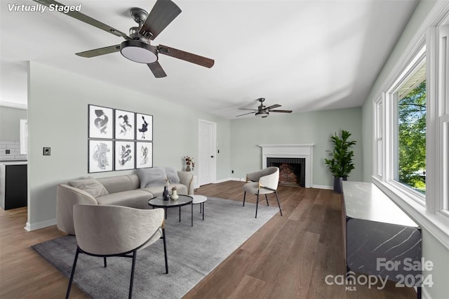 living room featuring ceiling fan, dark hardwood / wood-style flooring, and a fireplace