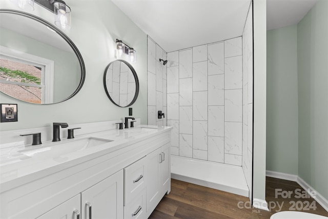 bathroom featuring vanity, a tile shower, toilet, and hardwood / wood-style floors