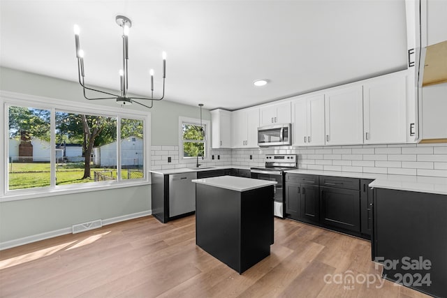 kitchen featuring appliances with stainless steel finishes, sink, a kitchen island, hanging light fixtures, and light hardwood / wood-style flooring